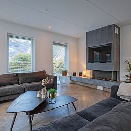 Gemuetliche Sitzecke mit Kamin in der Villa Bloem en Bos, De Dennen, Texel, ideal fuer entspannte Abende.