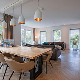 Geraeumiges Esszimmer im Bungalowpark 't Hoogelandt - Villa Bloem en Bos, Texel mit Blick auf die gruene Umgebung.