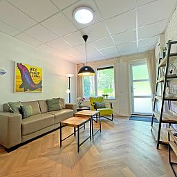 Lichte woonkamer van Appartement Bos en Duin 05, De Dennen, Texel met uitzicht op de groene omgeving.