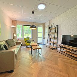 Ruime woonkamer in Appartement Bos en Duin 05, De Dennen, Texel met moderne inrichting en grote ramen.