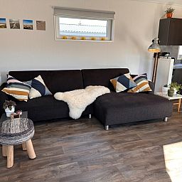 Spacious sitting area in Holiday Park de Bremakker - Bosveld 141, Texel with modern decoration and wooden floor.