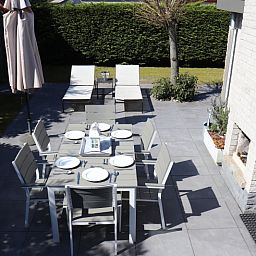 Aussenbereich des Ferienhauses Gortersmient 358 in De Dennen, Texel mit Esstisch und Liegestuehlen.