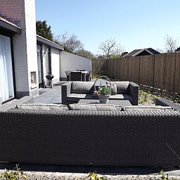 Zonovergoten terras bij Vakantiehuis Gortersmient 320 in De Dennen, Texel, met stijlvolle loungeset voor ultiem relaxen op de Waddeneilanden.