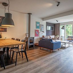 Ruime eet- en zithoek in Bungalowpark Gortersmient - Blommenzee, De Dennen, Texel met uitzicht op tuin.