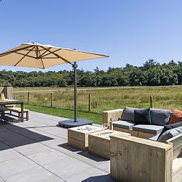 Sonnige Terrasse des Ferienhauses 1 in De Dennen Texel, ideal zum Entspannen auf den Watteninseln.