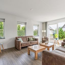Helles Wohnzimmer von Bungalowpark 't Hoogelandt - Villa 106F, Texel, mit Blick auf den Garten und die gemuetliche Sitzecke.