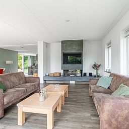 Geraeumiges Wohnzimmer in der Villa 106F, Bungalowpark 't Hoogelandt, Texel, mit modernem Mobiliar und Kamin.
