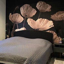 Attractive bedroom in Helianthus vacation home, De Dennen, Texel with floral wallpaper.