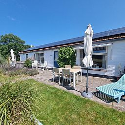 Ruim terras van Boszicht in De Dennen, Texel met ligstoelen en parasol.