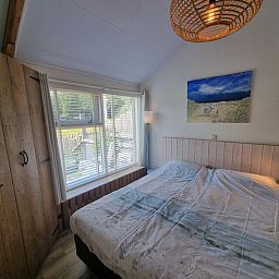 Sfeervolle slaapkamer in Boszicht vakantiehuis, De Dennen, Texel met houten details.