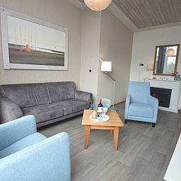 Gemuetliches Wohnzimmer in Lelie, De Dennen, Texel mit bequemen Stuehlen und Kunst an der Wand.