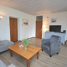 Geraeumiges Wohnzimmer des Ferienhauses Iris in De Dennen, Texel mit Fernseher und Dekoration.