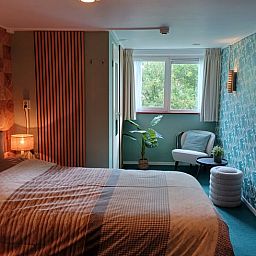 Stijlvolle slaapkamer met bloemenbehang in Huisje in Oosterend, Waddeneilanden.