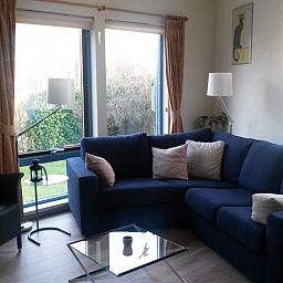 Cozy living room in Glissando bungalow, Midsland Noord, Terschelling with comfortable blue sofa.