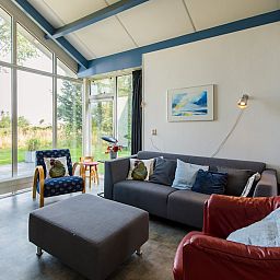 Gezellige woonkamer van Duinvilla 6 in Hollum, Ameland met grote ramen en uitzicht op de natuur van de Waddeneilanden.
