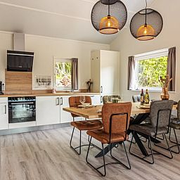 Moderne Kueche im Ferienhaus in Nes, Ameland, mit Essbereich und viel Licht.