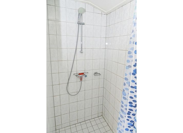 Rustikales Aeusseres des Coming Well Ferienhauses in De Cocksdorp, Texel mit gruener Umgebung.