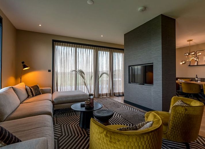 Gemuetliches Wohnzimmer im Ferienhaus in De Cocksdorp, Texel mit Blick auf gruene Felder.