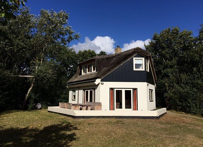 Velduil vakantiehuis in De Cocksdorp, Texel met rieten dak en groene omgeving.