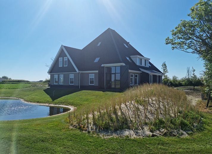 Ferienhaus De Muy in De Cocksdorp, Texel mit Blick auf den Teich und die gruene Umgebung.