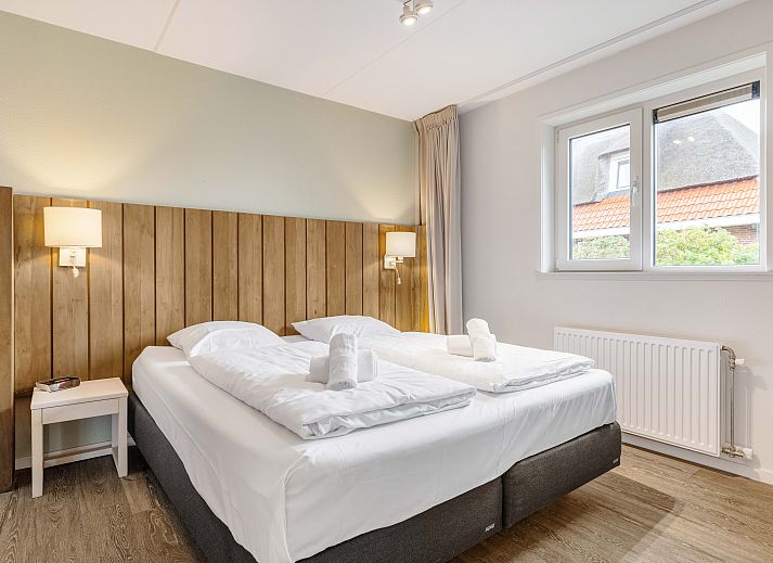 Cozy living room in Sluftervallei 8-person bungalow, De Cocksdorp, Texel. Comfortable sitting area with fireplace and views of nature.