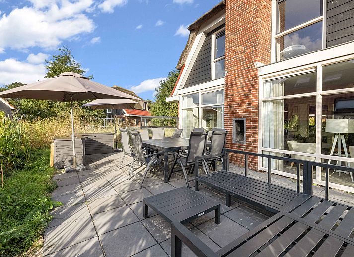 Cozy living room in Sluftervallei 8-person bungalow, De Cocksdorp, Texel. Comfortable sitting area with fireplace and views of nature.