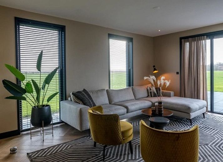 Illuminated evening view of 6 person vacation home in De Cocksdorp Texel with terrace.