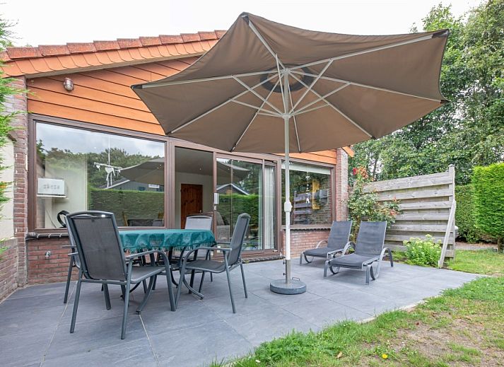 Geniessen Sie die Terrasse des Ferienhauses Slufterhoek 102 in De Cocksdorp, Texel, mit bequemen Stuehlen und einem grossen Sonnenschirm.