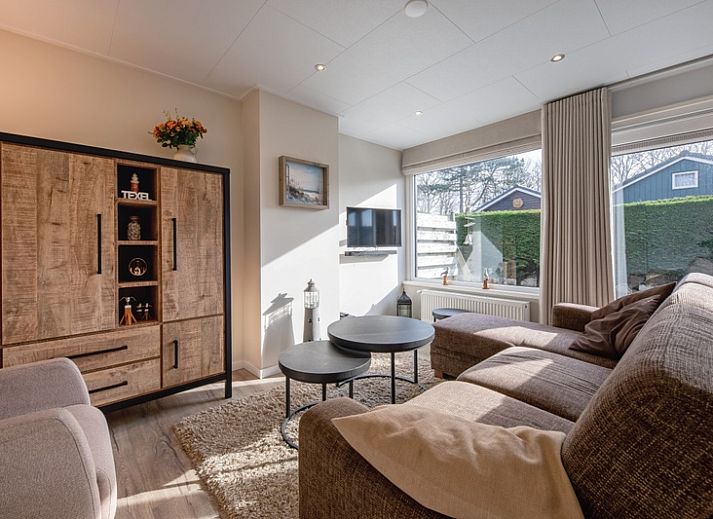 Geniessen Sie die Terrasse des Ferienhauses Slufterhoek 102 in De Cocksdorp, Texel, mit bequemen Stuehlen und einem grossen Sonnenschirm.