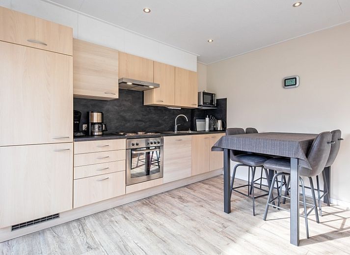 Geniessen Sie die Terrasse des Ferienhauses Slufterhoek 102 in De Cocksdorp, Texel, mit bequemen Stuehlen und einem grossen Sonnenschirm.