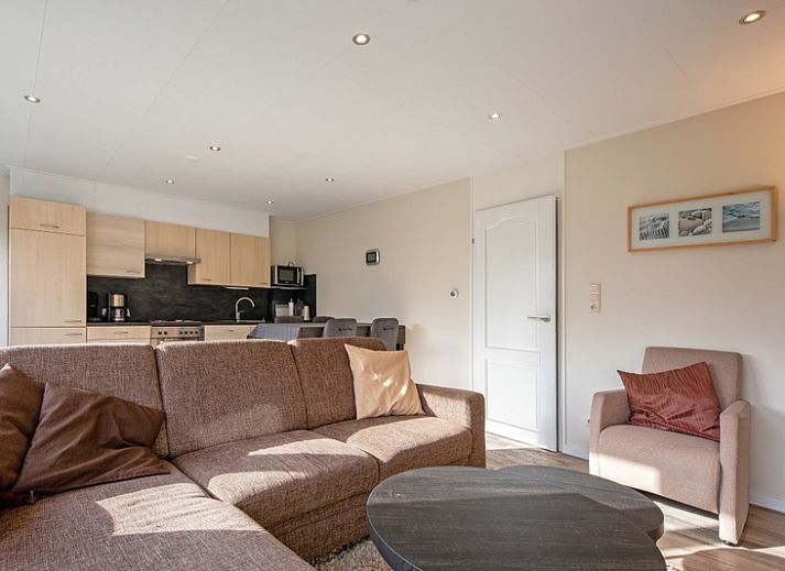 Geniessen Sie die Terrasse des Ferienhauses Slufterhoek 102 in De Cocksdorp, Texel, mit bequemen Stuehlen und einem grossen Sonnenschirm.