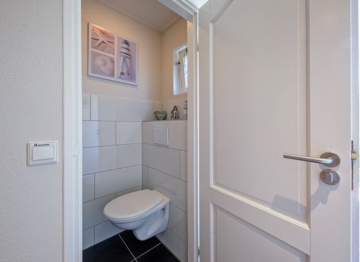 Entspannen Sie sich im gemuetlichen Wohnzimmer des Ferienhauses Slufterhoek 102, De Cocksdorp, Texel mit einem grossen Sofa und viel Tageslicht.