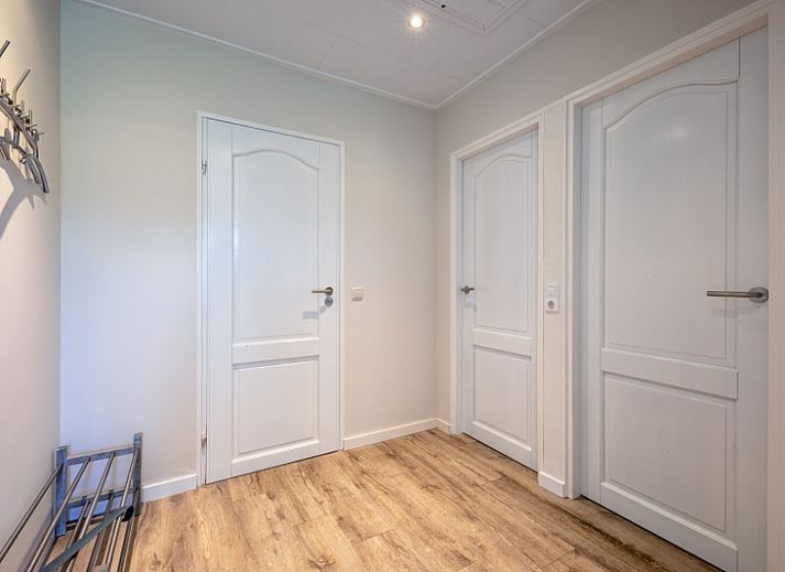 Entspannen Sie sich im gemuetlichen Wohnzimmer des Ferienhauses Slufterhoek 102, De Cocksdorp, Texel mit einem grossen Sofa und viel Tageslicht.