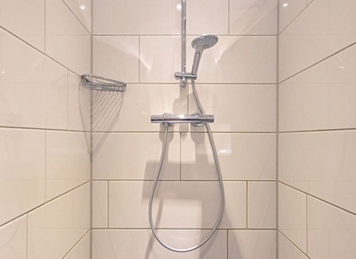 Entspannen Sie sich im gemuetlichen Wohnzimmer des Ferienhauses Slufterhoek 102, De Cocksdorp, Texel mit einem grossen Sofa und viel Tageslicht.