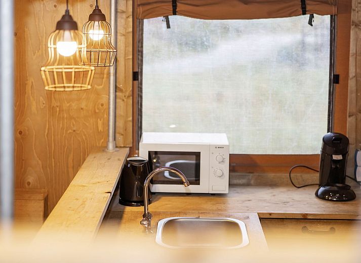 Cozy interior of Sluftervallei safari tent on Texel with wooden furnishings.