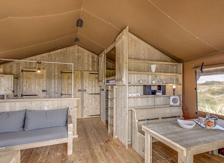 Cozy interior of Sluftervallei safari tent on Texel with wooden furnishings.