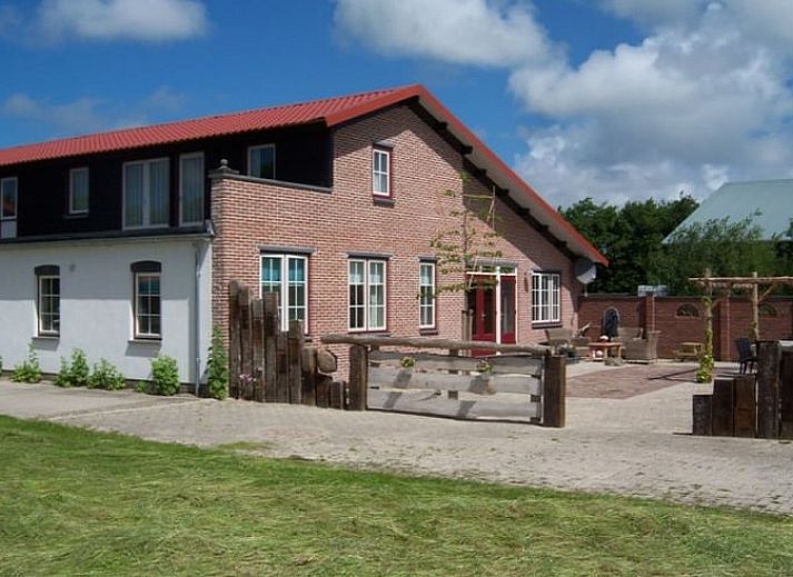 Charmante bakstenen gevel van Huisje in De Cocksdorp, Texel, met ruim terras voor ontspanning.