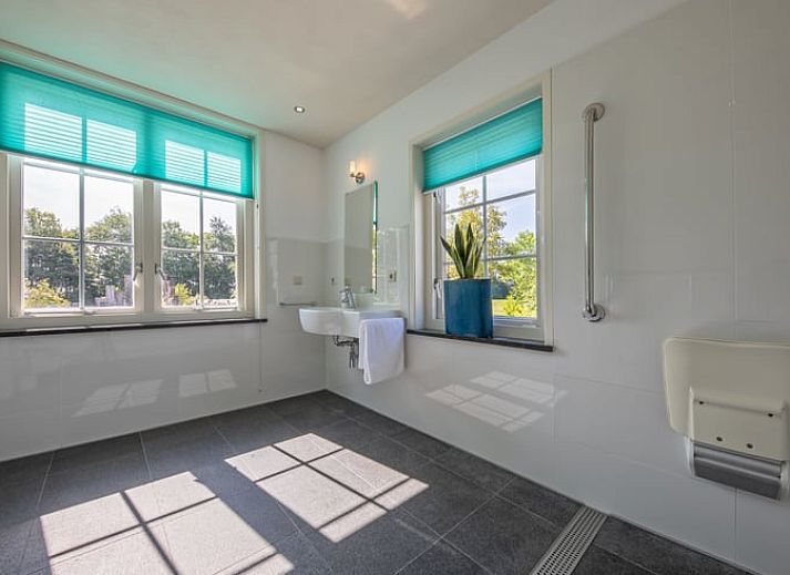 Achtertuin van Huisje in De Cocksdorp, Texel, met kleurrijke planten en uitnodigend terras.