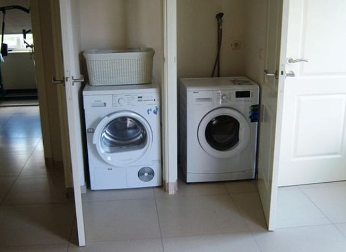 Achtertuin van Huisje in De Cocksdorp, Texel, met kleurrijke planten en uitnodigend terras.