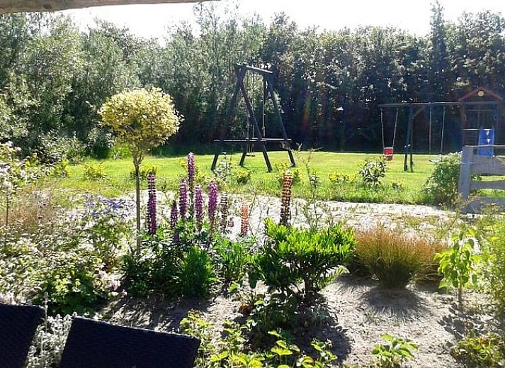 Gezellige zithoek in Huisje in De Cocksdorp, Texel, met groene muur en moderne voorzieningen.