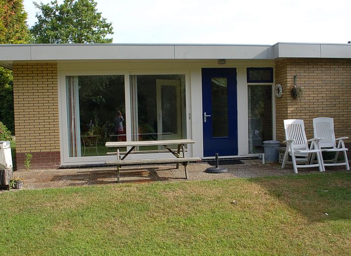 Gemuetliche Terrasse des Bungalows Tamarisk 212 in De Cocksdorp, Texel, mit Sitzgelegenheiten im Garten und gruener Umgebung.