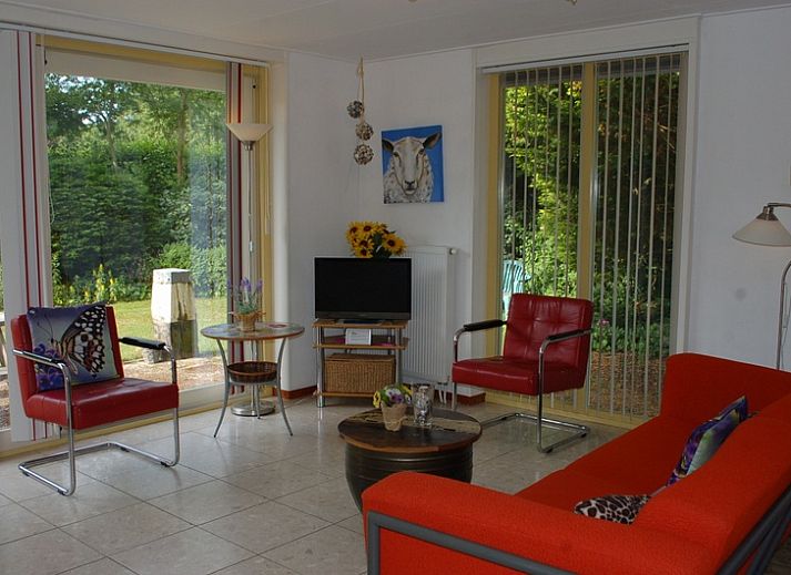 Gemuetliche Terrasse des Bungalows Tamarisk 212 in De Cocksdorp, Texel, mit Sitzgelegenheiten im Garten und gruener Umgebung.