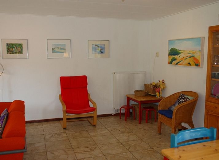 Gemuetliche Terrasse des Bungalows Tamarisk 212 in De Cocksdorp, Texel, mit Sitzgelegenheiten im Garten und gruener Umgebung.