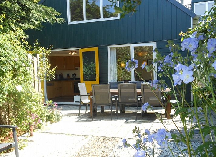 Geniessen Sie den sonnigen Garten des Ferienhauses Ganzenvlucht in De Cocksdorp, Texel, mit einer grossen Terrasse und bunten Blumen.