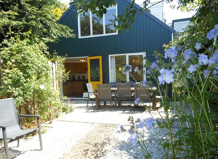 Geniessen Sie den sonnigen Garten des Ferienhauses Ganzenvlucht in De Cocksdorp, Texel, mit einer grossen Terrasse und bunten Blumen.