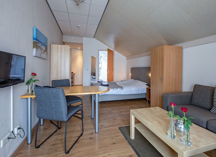 Geraeumiges Schlafzimmer im Ferienhaus Typ 1 - 2100 in De Cocksdorp, Texel, mit bequemem Bett und Sitzecke.