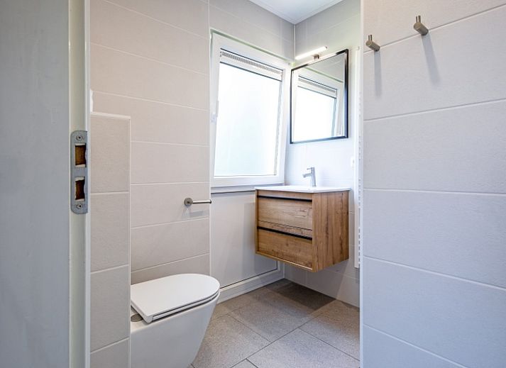 Gemuetliches Wohnzimmer im Ferienhaus Slufterhoek 132, De Cocksdorp, Texel, mit bequemen Sofas und Blick auf den Garten