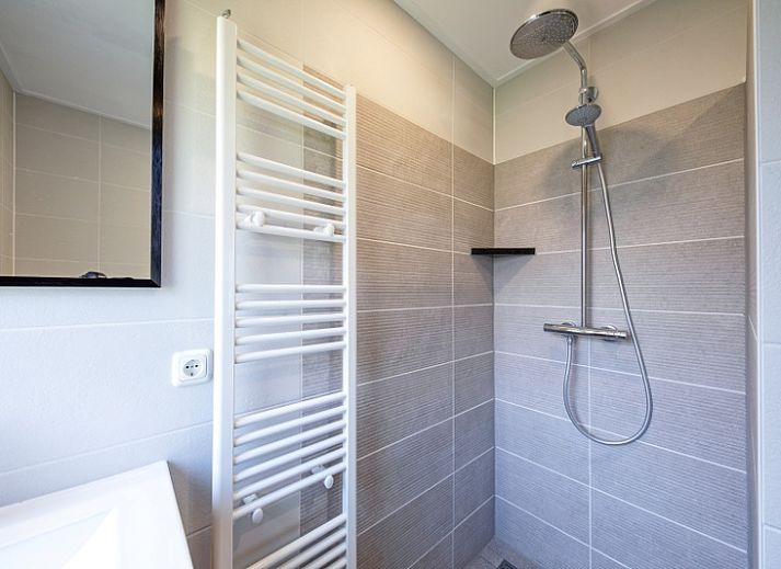 Gemuetliches Wohnzimmer im Ferienhaus Slufterhoek 132, De Cocksdorp, Texel, mit bequemen Sofas und Blick auf den Garten