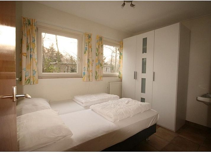 Gemuetliche Sitzecke im Bungalowpark Slufteroord, De Cocksdorp Texel, mit bequemem Sofa und Blick auf den gruenen Garten.