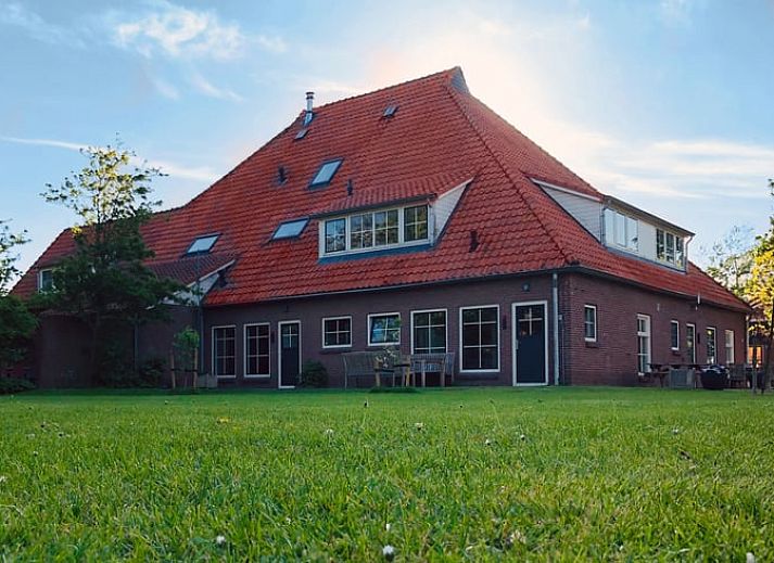 Vorderseite eines Ferienhauses in De Cocksdorp, Texel, mit Gruenpflanzen und Backsteinfassade.